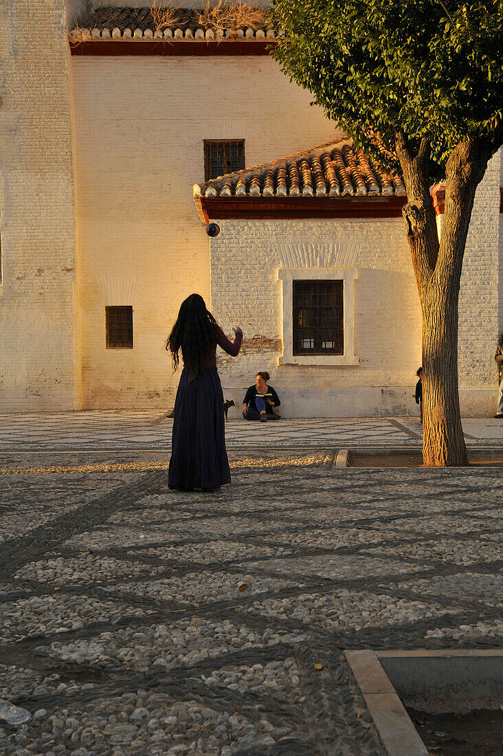 Frau wirft Ball in die Luft, Frau spielt in der Abendsonne mit Ball auf dem Mirador de San Nicolas, Granada, Andalusien, Spanien, Europa