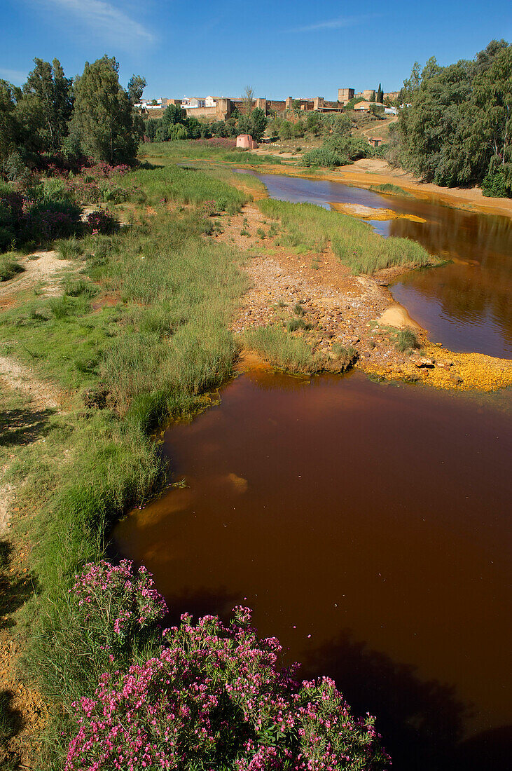 Rot gefärbtes Wasser des Rio Tinte bei Niebla, Festung im Hintergrund, Huelva, Andalusien, Spanien