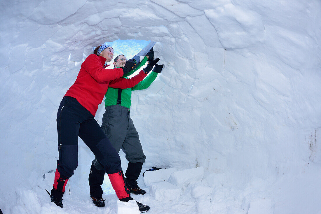 Zwei Personen bauen Iglu, Chiemgauer Alpen, Chiemgau, Oberbayern, Bayern, Deutschland