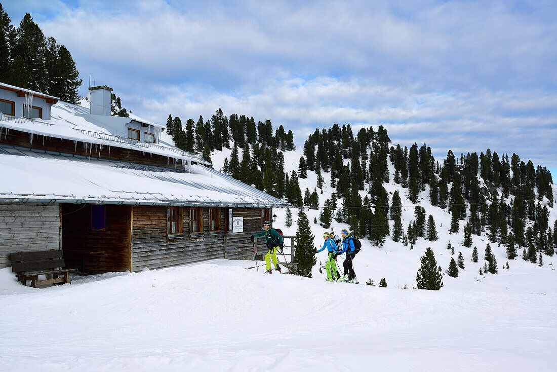 Three persons back-country skiing in front of Neue Bamberger Huette, Kurzer Grund, Kitzbuehel range, Tyrol, Austria