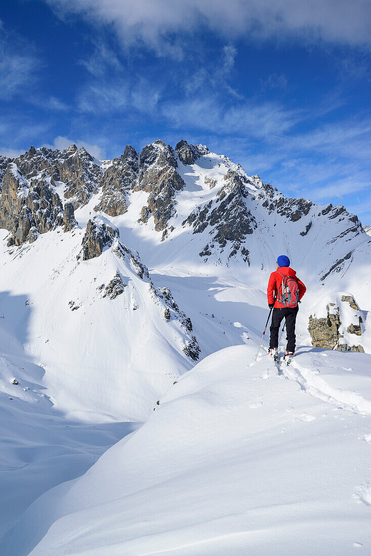 Woman back-country skiing looking towards valley Vallonasso di Sautron, Monte Soubeyran, Valle Maira, Cottian Alps, Piedmont, Italy