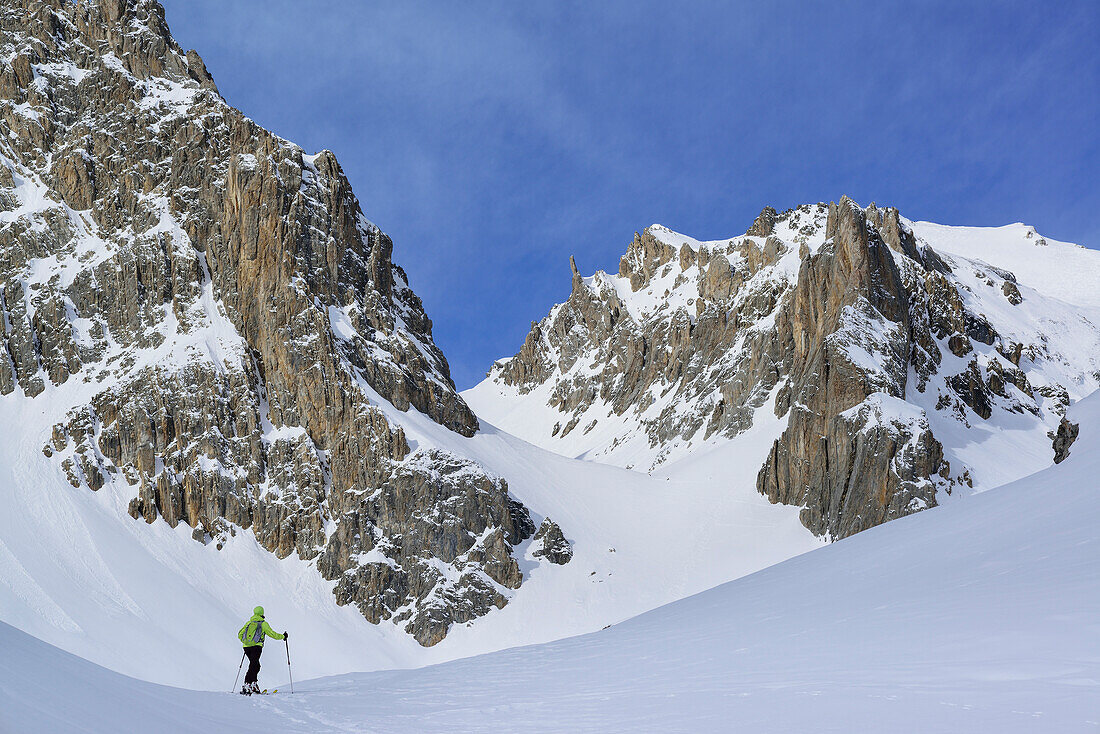 Woman back-country skiing ascending towards Colle d'Enchiausa, Valle Enchiausa, Valle Maira, Cottian Alps, Piedmont, Italy