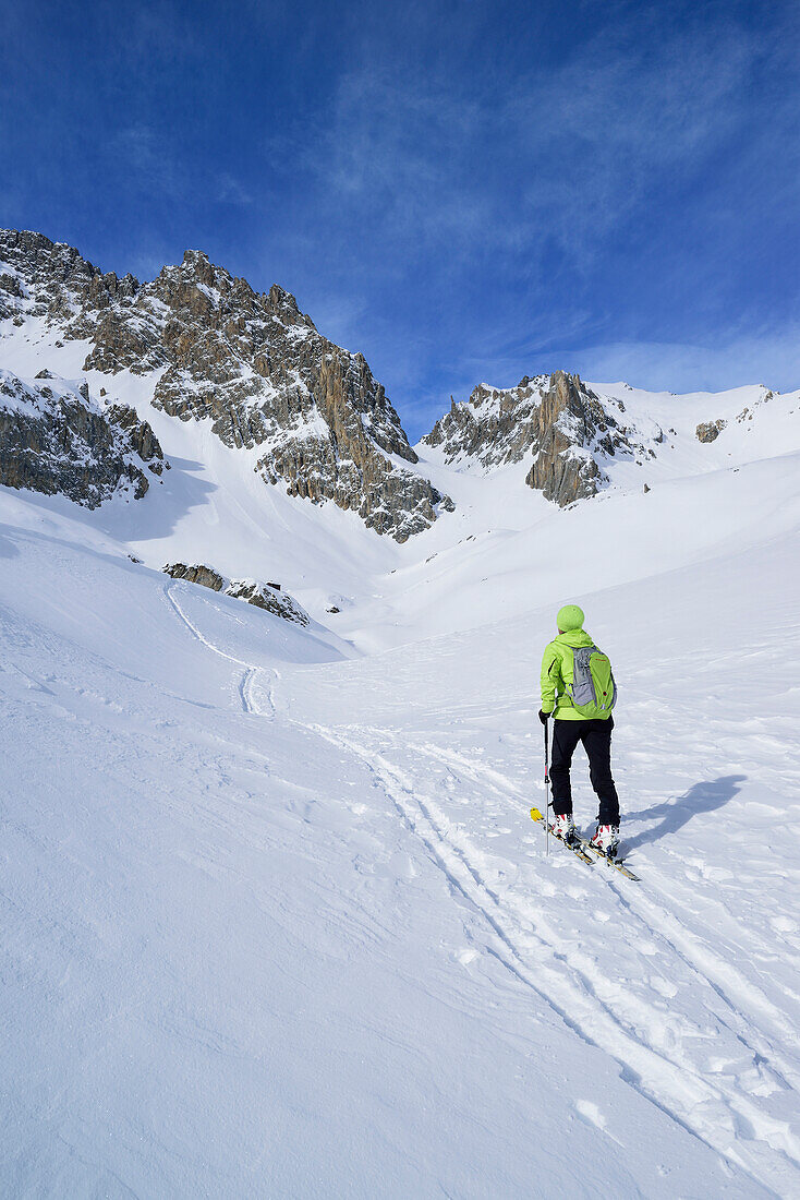 Woman back-country skiing ascending towards Colle d'Enchiausa, view to Monte Oronaye, Valle Enchiausa, Valle Maira, Cottian Alps, Piedmont, Italy