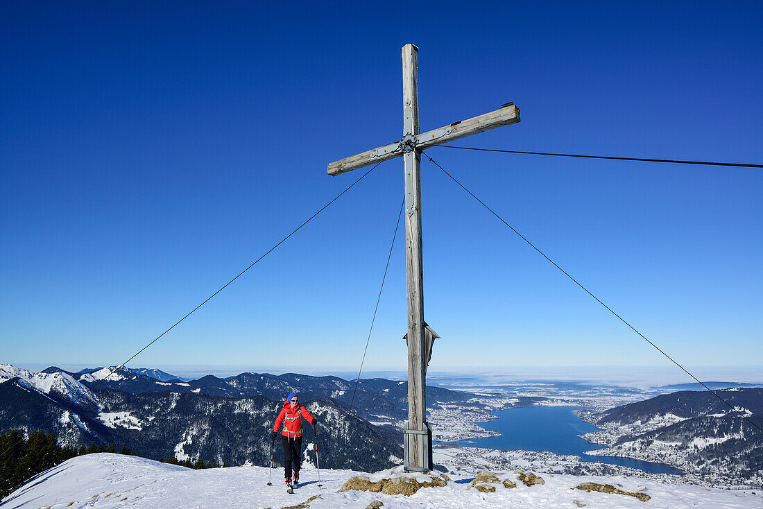 Frau auf Skitour am Gipfel des Setzberg, Tegernsee im Hintergrund, Setzberg, Bayerische Alpen, Oberbayern, Bayern, Deutschland