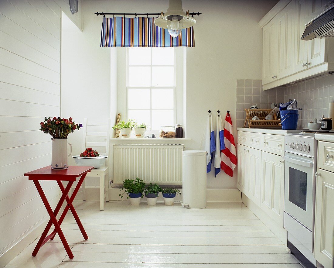 weiße Küche im Landhausstil mit rotem Klapptisch