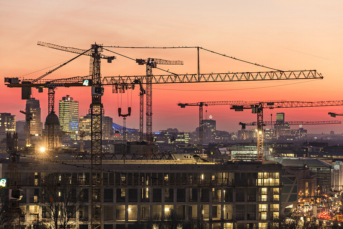 Blick vom Alexanderplatz auf Baukräne in der Dämmerung über den Dächern von Berlin, Berlin, Deutschland