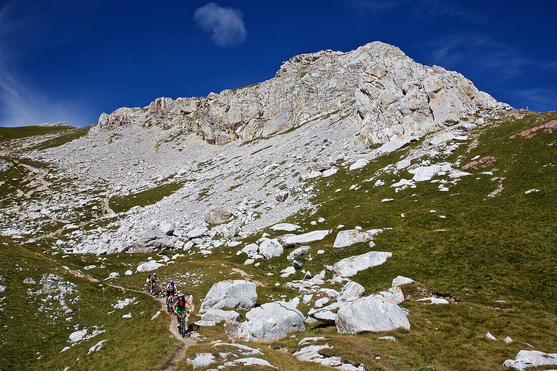 three mountain bikers on a single-trail at Latemar, Trentino Italy