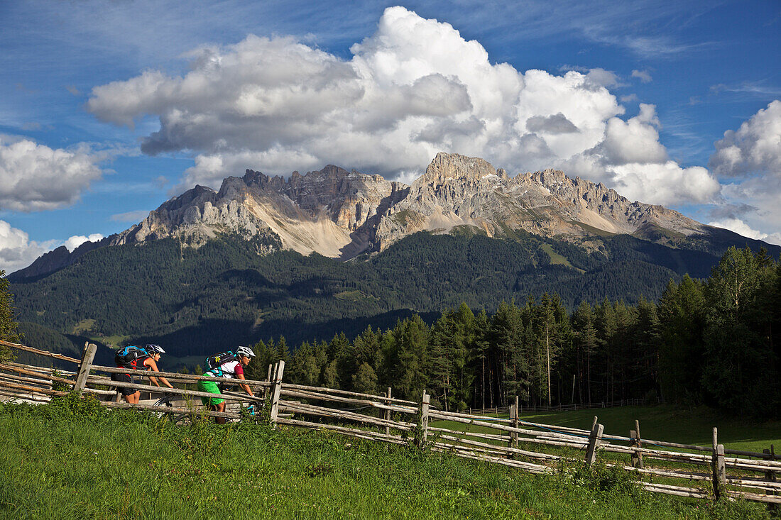 two mountain bikers near Deutschnofen, Latemar massif in the background, Trentino, Italy