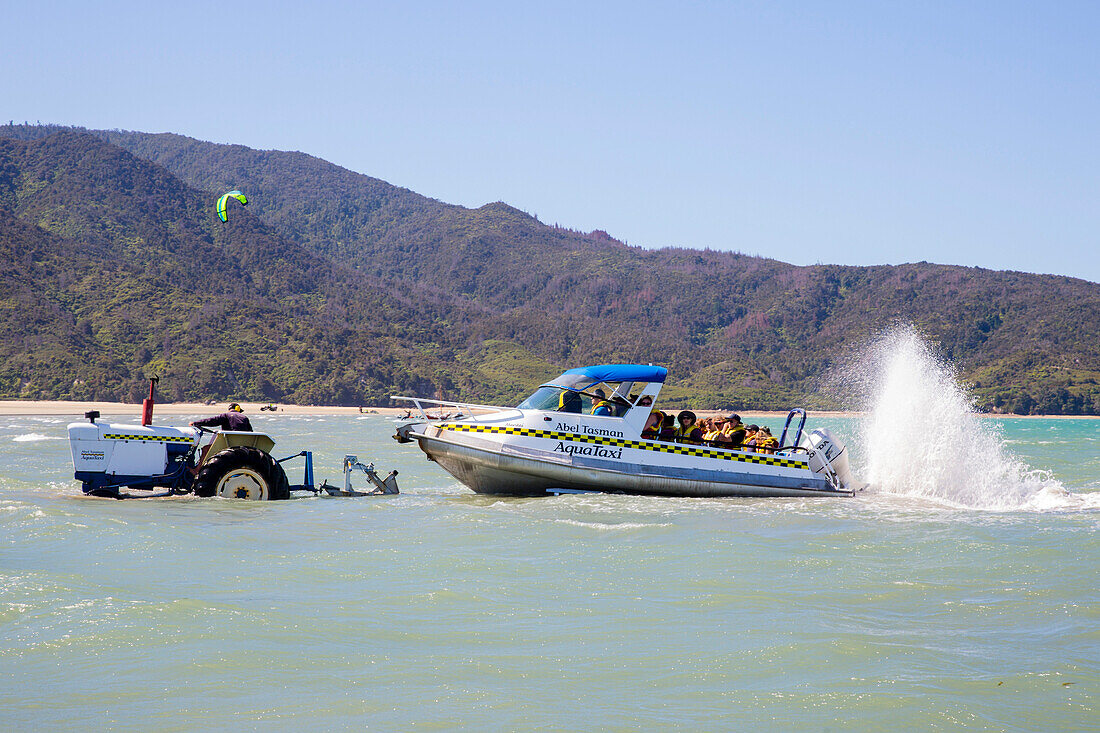 Taxiboote werden mit Traktor und Anhänger aus dem Meer geholt, Abel Tasman National Park, Südinsel, Neuseeland