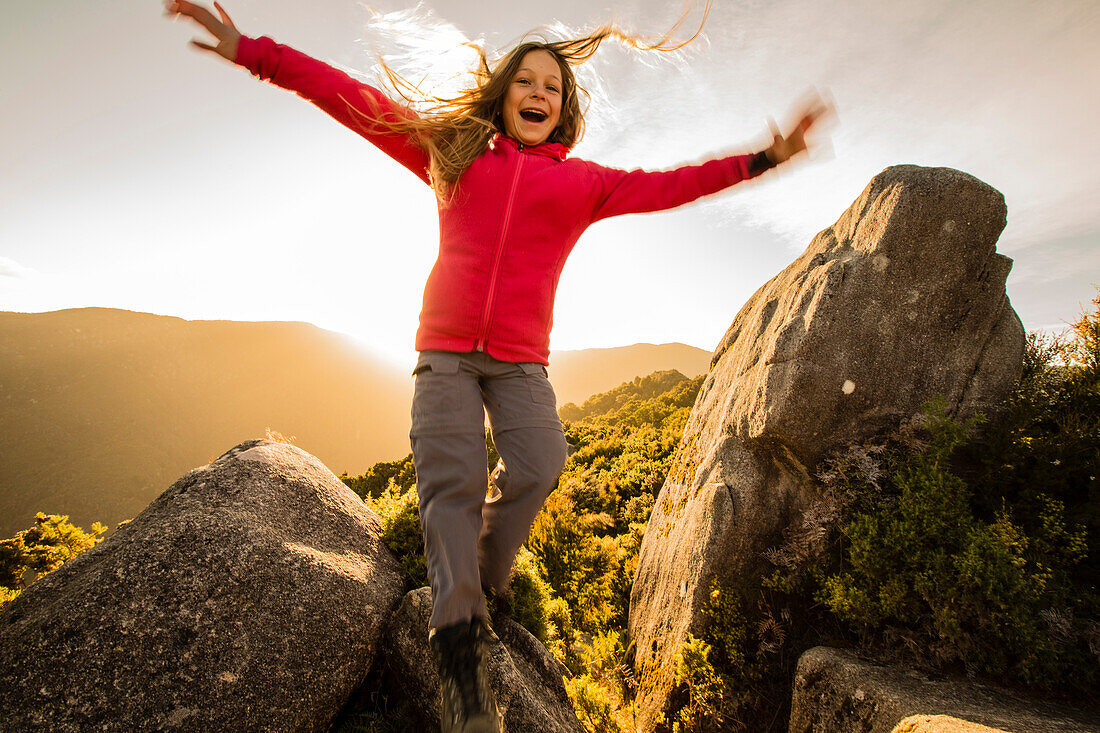 Ein Mädchen springt von einem Felsen, Castle Rocks, bei der Castle Rock Hut, Abel Tasman Nationalpark, Südinsel, Neuseeland