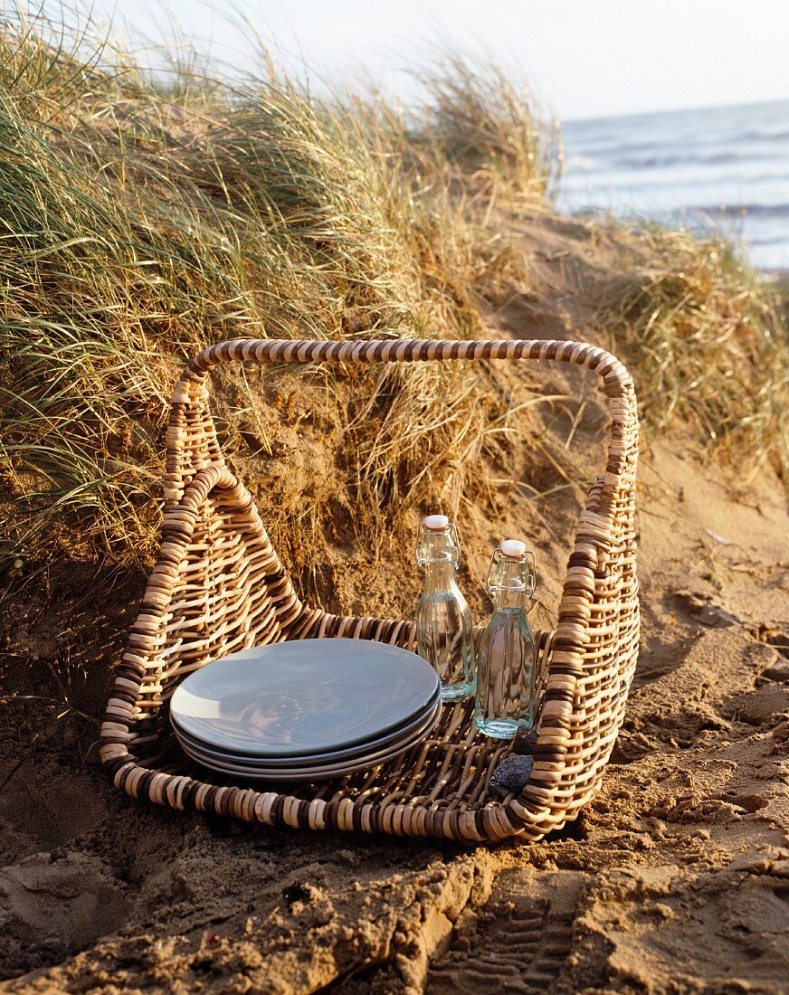 Picknickkorb auf Sandboden und Blick auf das Meer