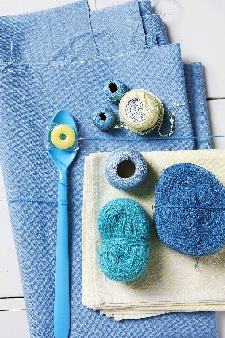 An arrangement comprising blue balls of wool on blue fabric