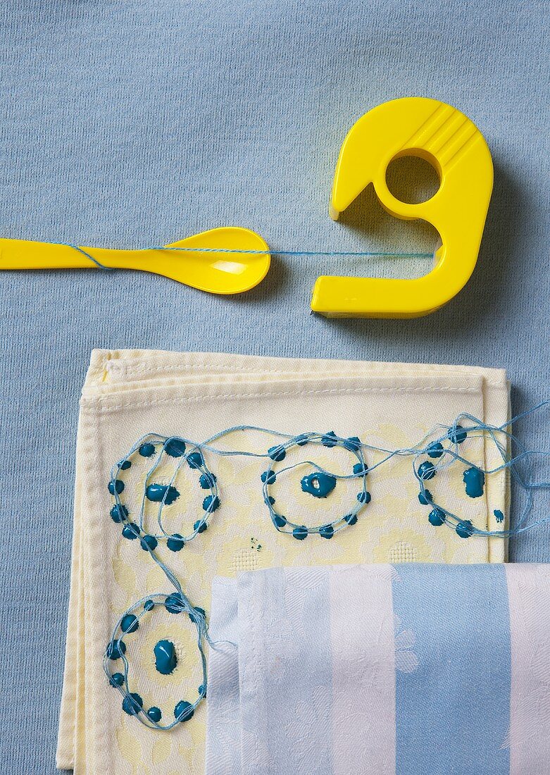 A yellow sticky tape dispenser and an embroidered cloth on a blue tablecloth