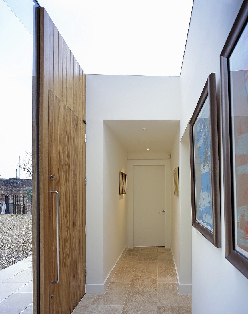 A modern entrance way painted white with a wooden front door