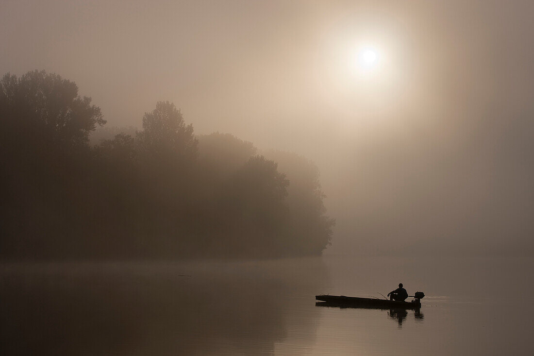 Fisherman on Tisza River on foggy morning, Hungary