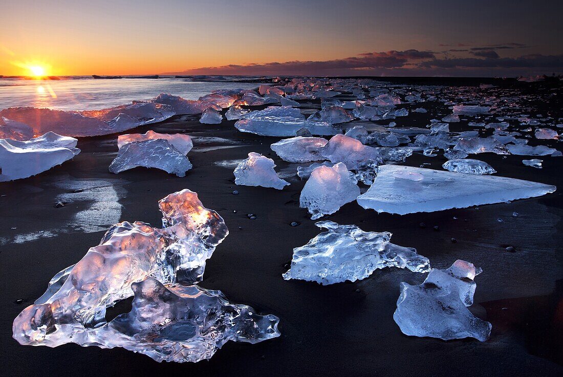 Chunks of ice on coastline near Jokulsarlon at sunset, Iceland