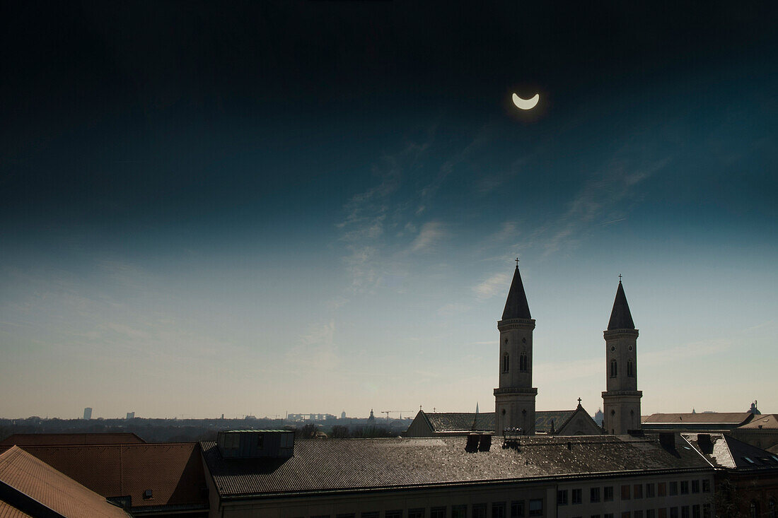 A partial eclipse of the sun over the rooftops of Munich, St. Ludwigkirche, Universitaetskirche, Schwabing, Bavaria, Germany