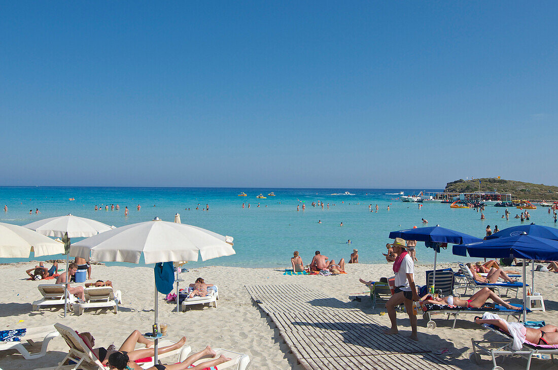 Sonnenschirme und Menschen am weissen Strand, Nissi Beach bei Agia Napa nordöstlich von Larnaka, Larnaca District, Zypern