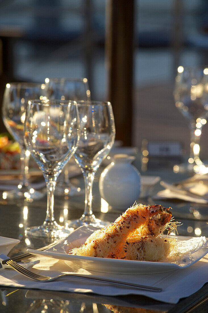 Gedeck mit Gläsern und Riesengarnelen asiatisch zubereitet im Gartenrestaurant mit Abendsonne im Le Meridien Hotel, Limassol, Limassol District, Zypern