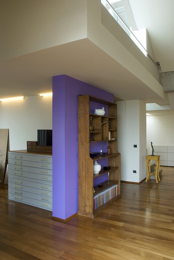 Open-plan living - a bookshelf in front of a purple wall
