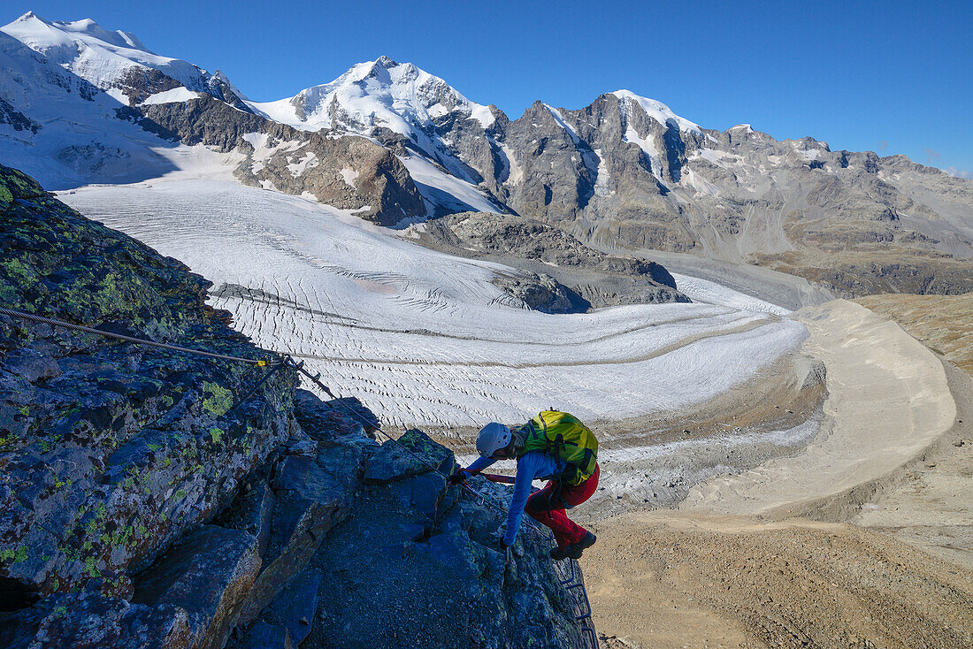 Woman climbing the via ferrata at Piz Trovat with view to Bellavista (3922 m), Piz Bernina (4049 m), Piz Morteratsch (3751 m) as well as Pers- and Morteratsch glacier, Engadin, Grisons, Switzerland