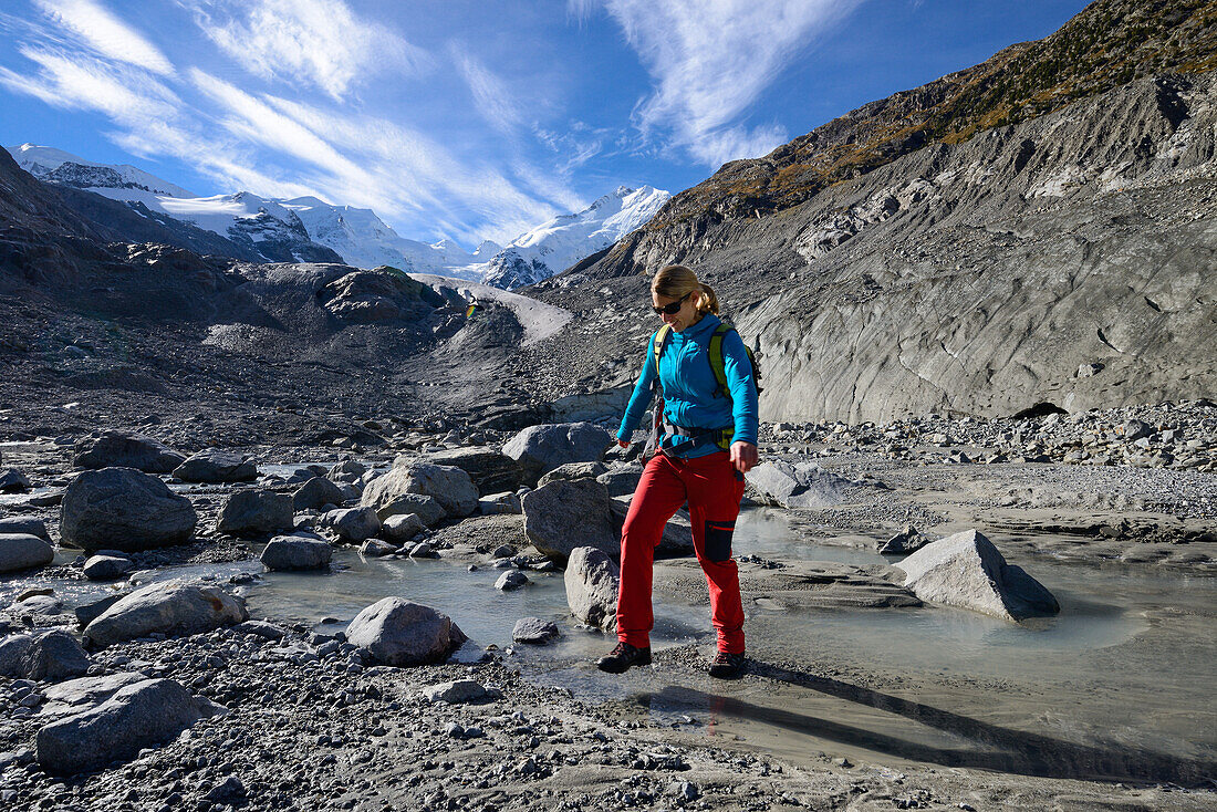 Woman crossing the Morteratsch Creek near the glacier mouth of Morteratsch glacier with view to Bellavista (3922 m), Piz Bernina (4049 m), Engadin, Grisons, Switzerland