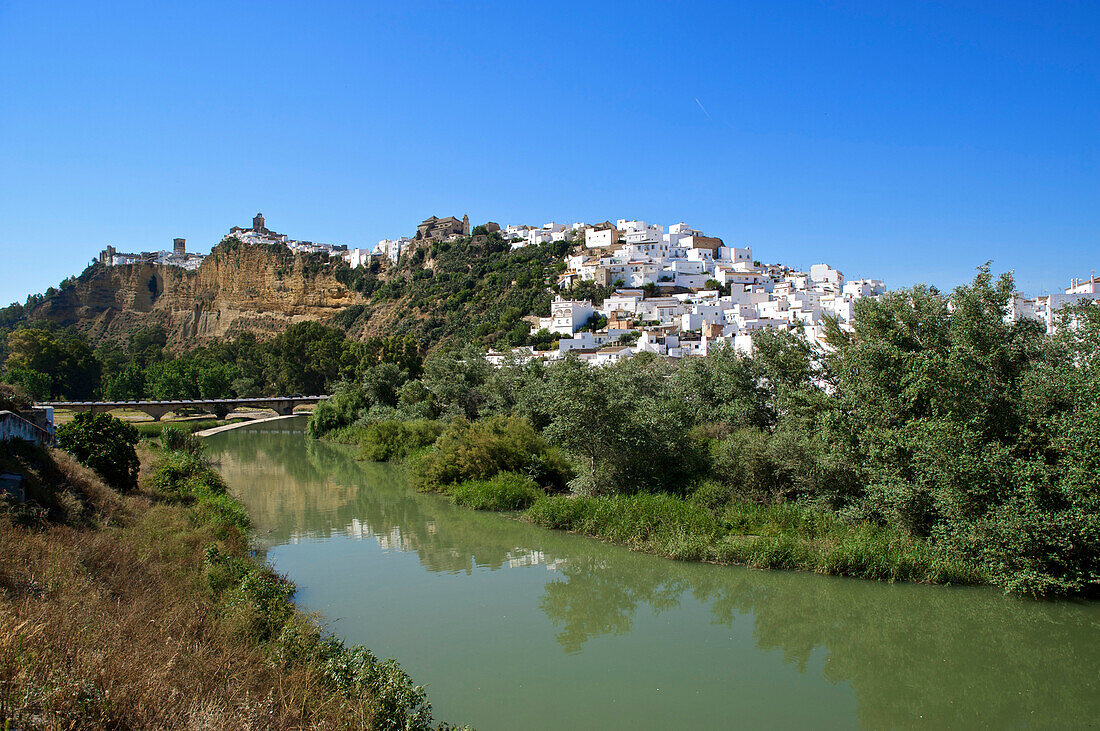Blick vom Fluss zur auf einem Berg liegenden weissen Stadt Arcos de la Frontera, Provinz Cadiz, Andalusien, Spanien