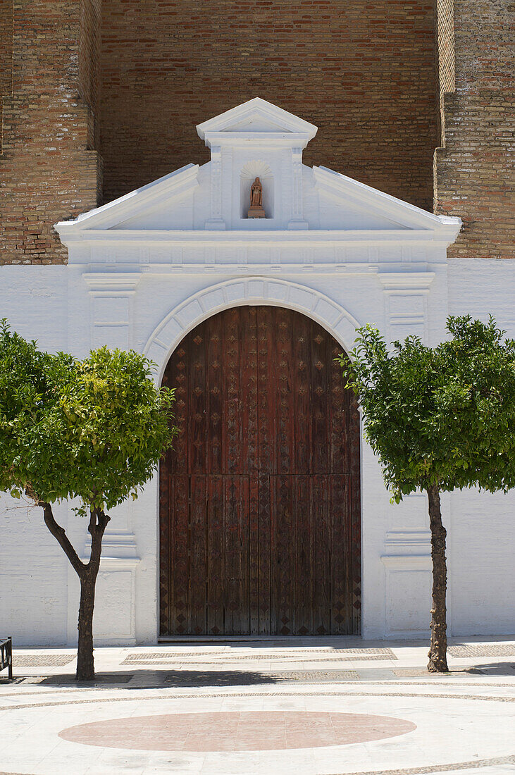 Door of the church Parroquia de Nuestra Senora de la Granada with two orange trees, Moguer, Provinz Huelva, Andalusia, Spain