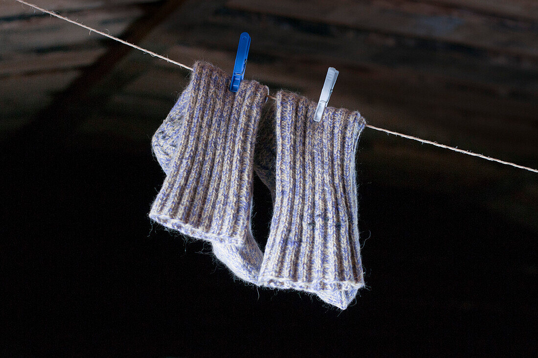 A pair of woollen socks on a clothes line, fixed with pegs in the national colours of Finland, Suomunruoktu Hut, Urho Kekkonen National Park, Finnish Lapland, Finland