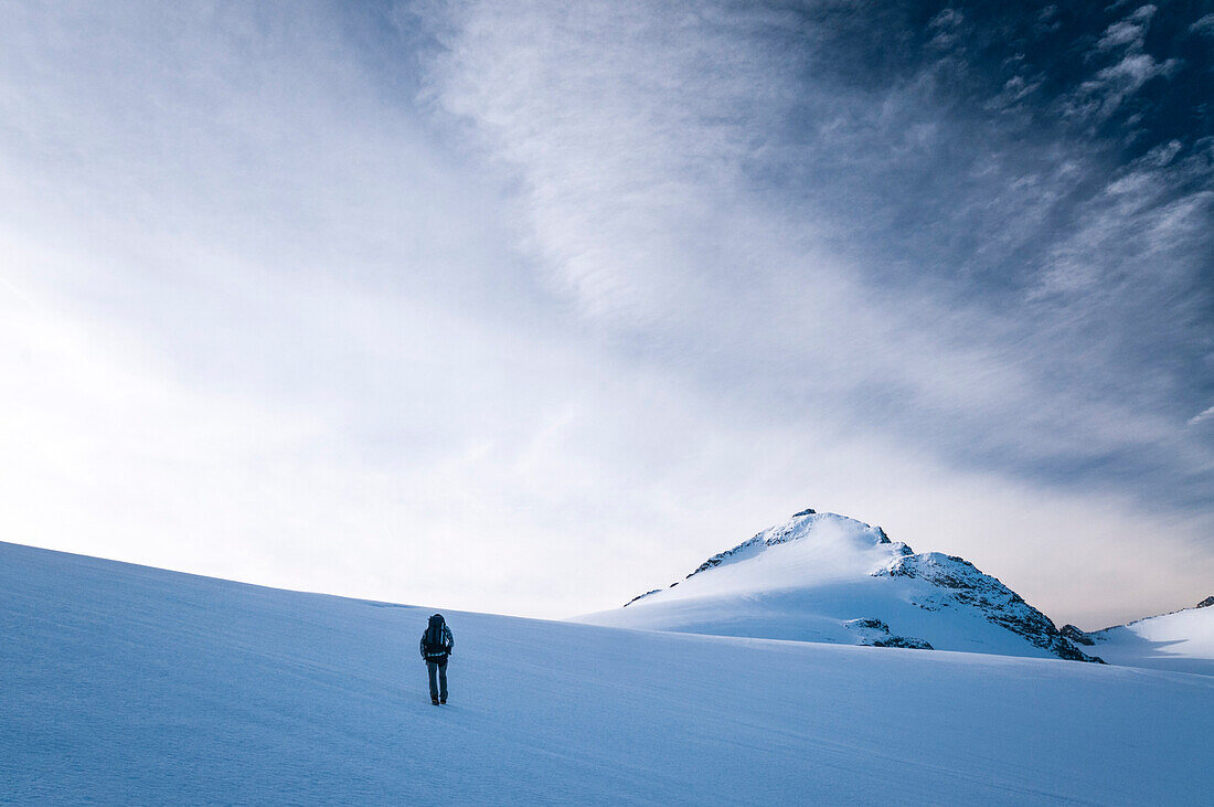 Ein Alpinwanderer ist unterwegs auf dem Gletscher namens Glatscher da Medel, im Hintergrund der Piz Medel, Bündner Alpen, Schweiz