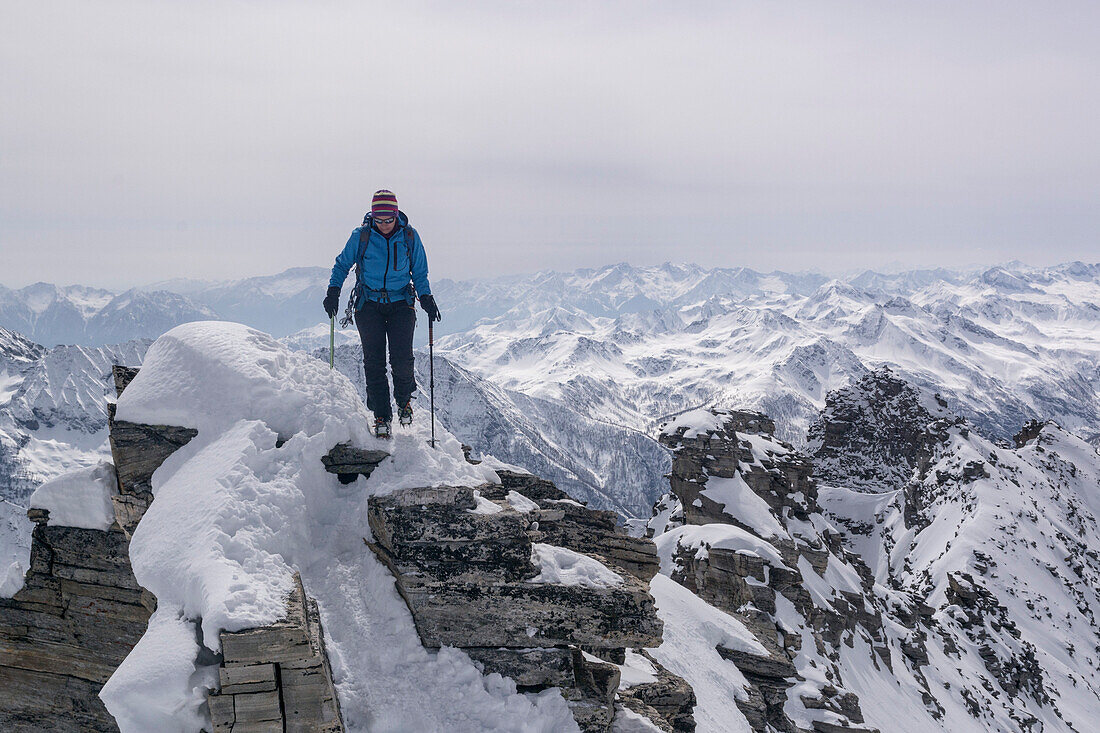 A female mountaineer walking on an exposed ridge, south ridge of Monte Leone, Lepontine Alps, canton of Valais and region of Piedmont, national border of Switzerland and Italy