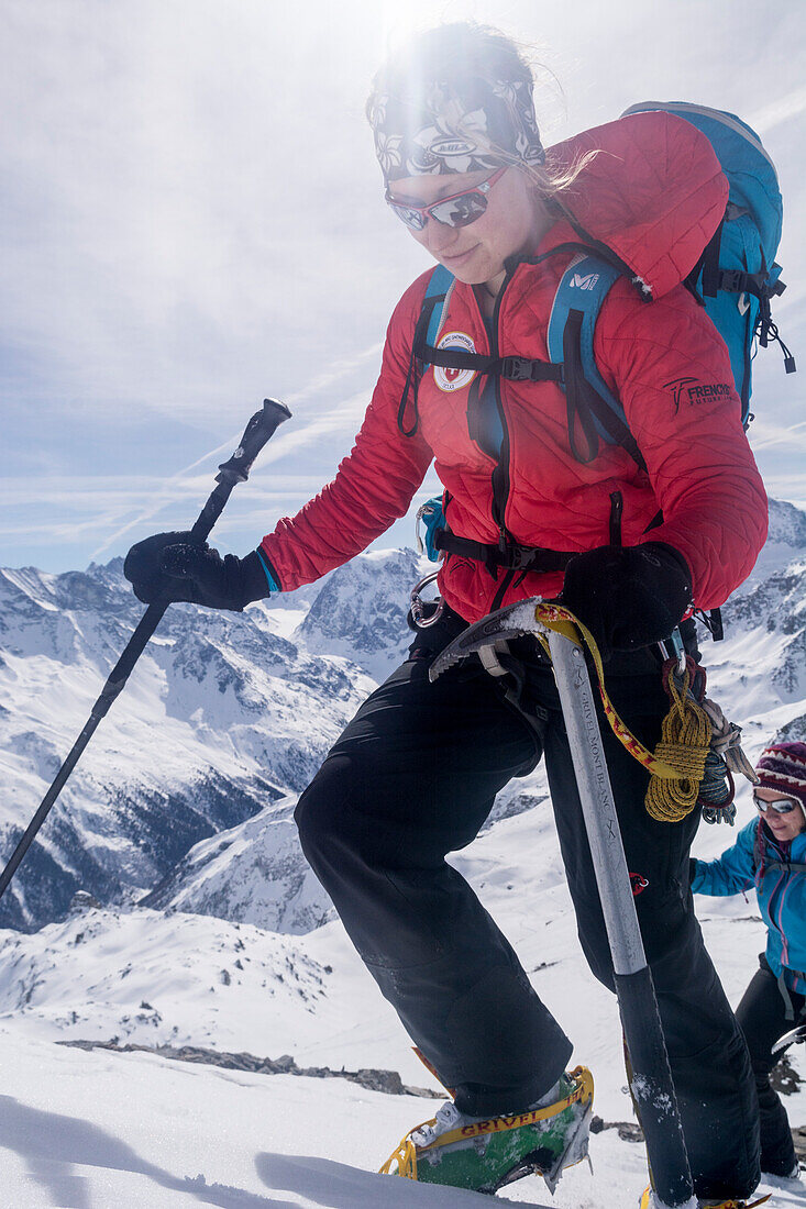 Two young female mountaneers ascending the snow-covered southwestern face of Mont de l‘Etoile with crampons and ice-axe and a pole, Val d‘Herens, Pennine Alps, canton of Valais, Switzerland