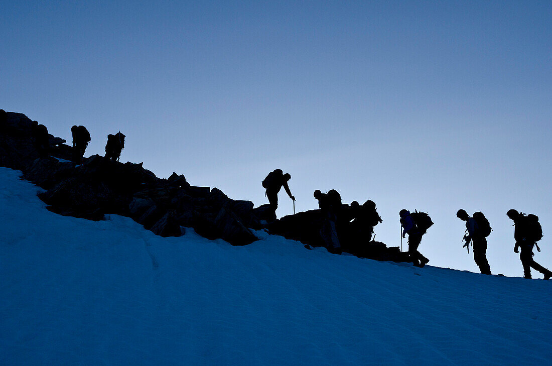 Bergsteiger früh morgens am Einstieg zum Südgrat des Gipfels namens Weissmies, Walliser Alpen, Kanton Wallis, Schweiz