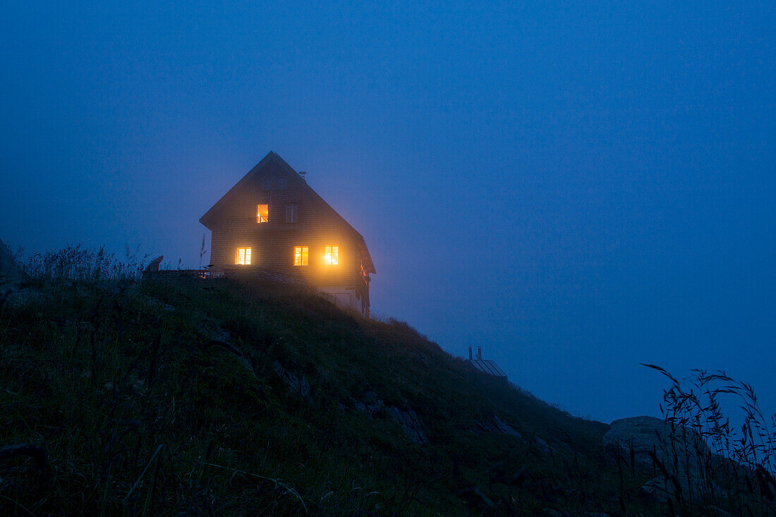 Die Fenster der Gaulihütte leuchten in der Abenddämmerung, Gauligebiet, Berner Alpen, Kanton Bern, Schweiz