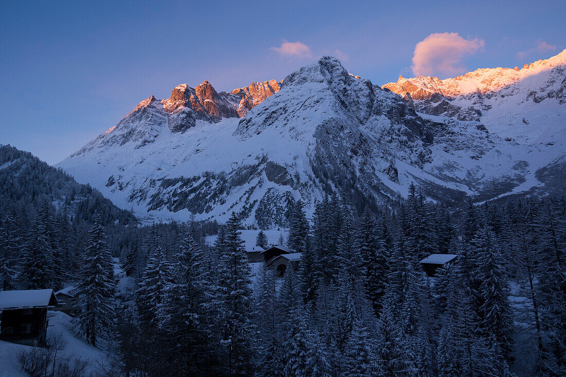 Häuser des Dorfs La Fouly am frühen Morgen, dahinter die Gipfel des Mont Grépillon im ersten Sonnenlicht, Val Ferret, Walliser Alpen, Kanton Wallis, Schweiz