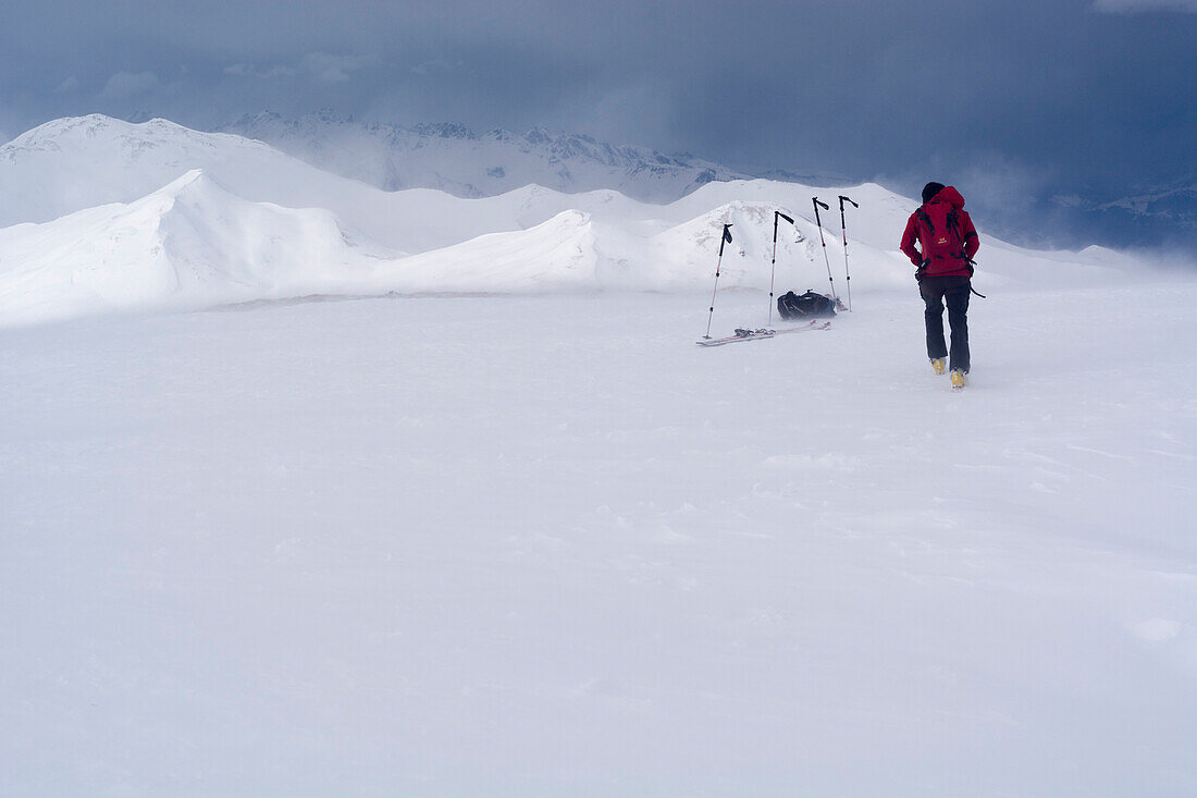 Ein Skitourengänger im Föhnsturm auf dem Gipfel des Mattjisch Horn, Hochtal Fondei, Bündner Alpen, Kanton Graubünden, Schweiz