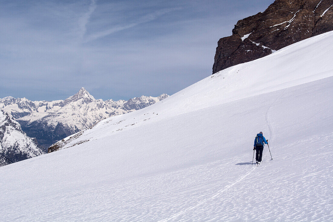Eine Skitourengängerin steigt auf Richtung Monte-Leone-Hütte, im Hintergrund das Bietschhorn, Simplongebiet, Lepontinische Alpen, Kanton Wallis, Schweiz