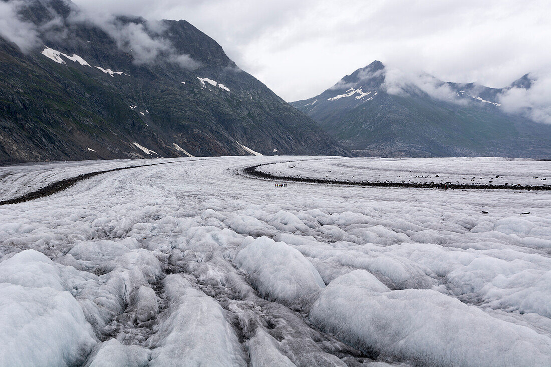 Der Grosse Aletschgletscher mit seinen typischen Mittelmoränen, in der Bildmitte eine Gruppe von Alpinisten, weiter hinten der Einschnitt des Tals von Märjelen, Berner Alpen, Kanton Wallis, Schweiz