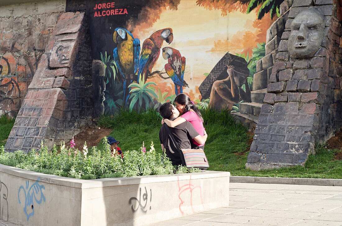 Ein junges Paar küsst sich vor einem Wandbild des Künstlers Jorge Alcoreza, ein Junge schaut verstohlen zu, La Paz, Bolivien