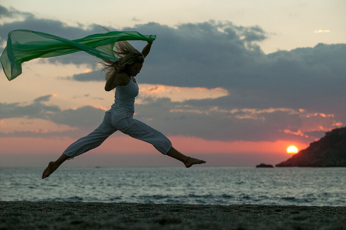 Junge Frau springt am Strand, Kreta, Griechenland