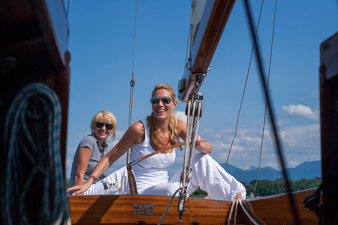 Two young women on a sailing boat, Chiemsee, Bavaria, Germany