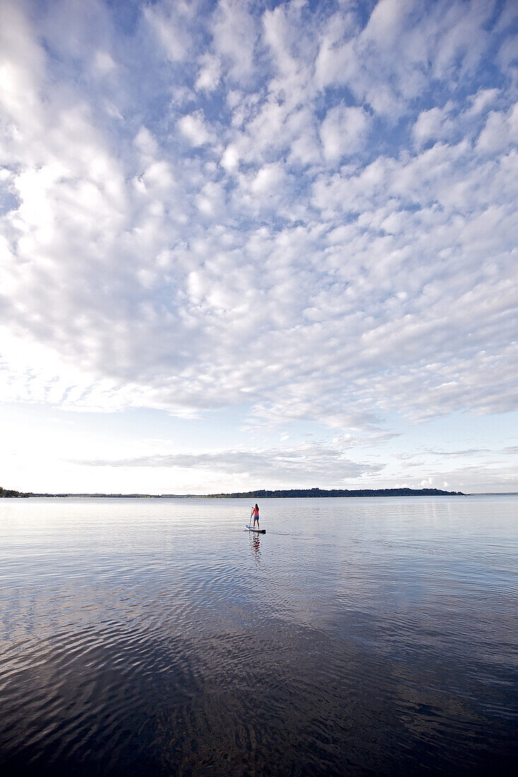 Woman stand up paddling on lake Chiemsee, Chiemgau, Bavaria, Germany