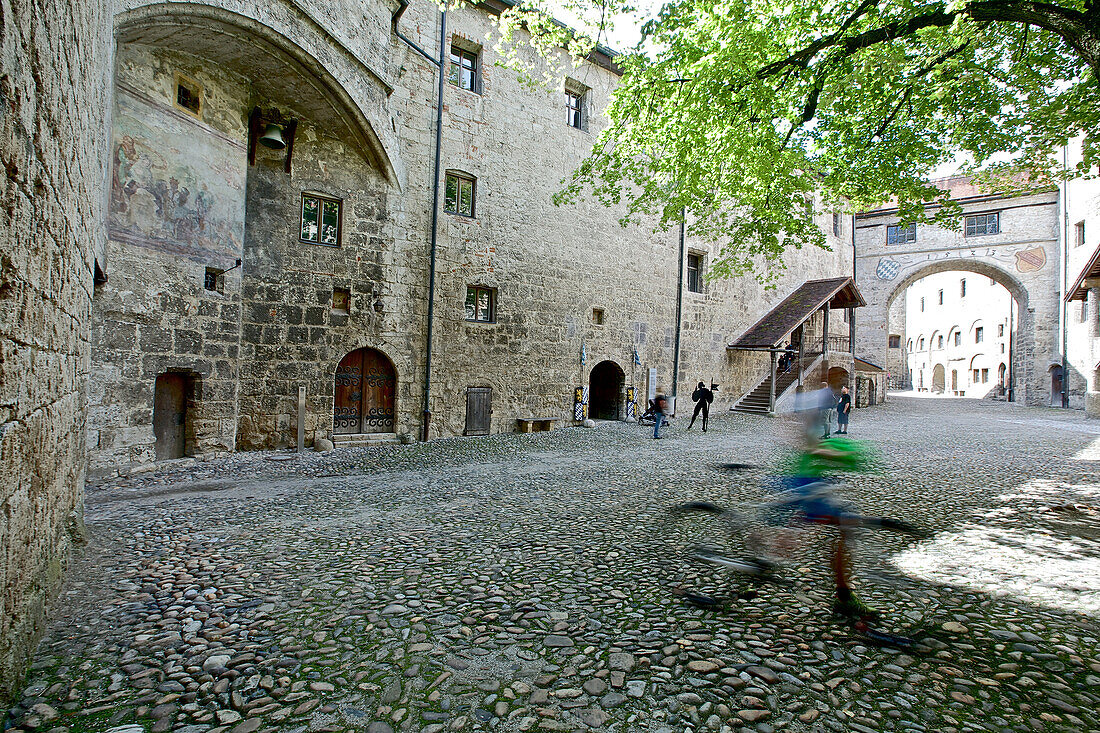 Woman pushing a bicycle over a castle courtyard, Burghausen, Chiemgau, Bavaria, Germany