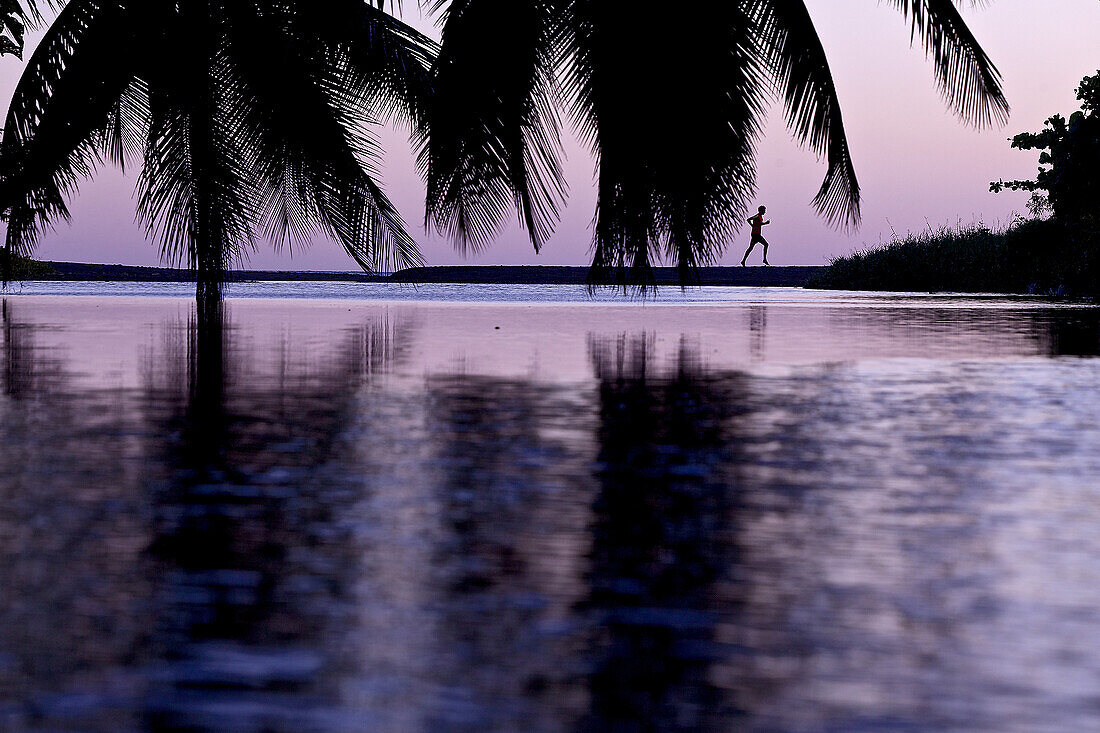 Mann läuft am Strand im Sonnenuntergang, Dominica, Kleine Antillen, Karibik