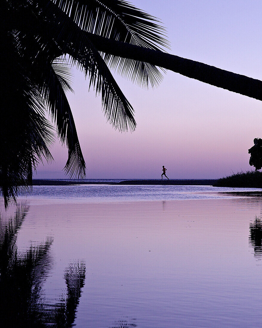 Mann läuft am Strand im Sonnenuntergang, Dominica, Kleine Antillen, Karibik