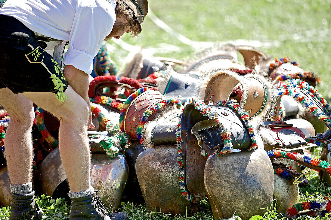 Mann in Tracht bei einem Haufen Kuhglocken, Viehscheid, Allgäu, Bayern, Deutschland