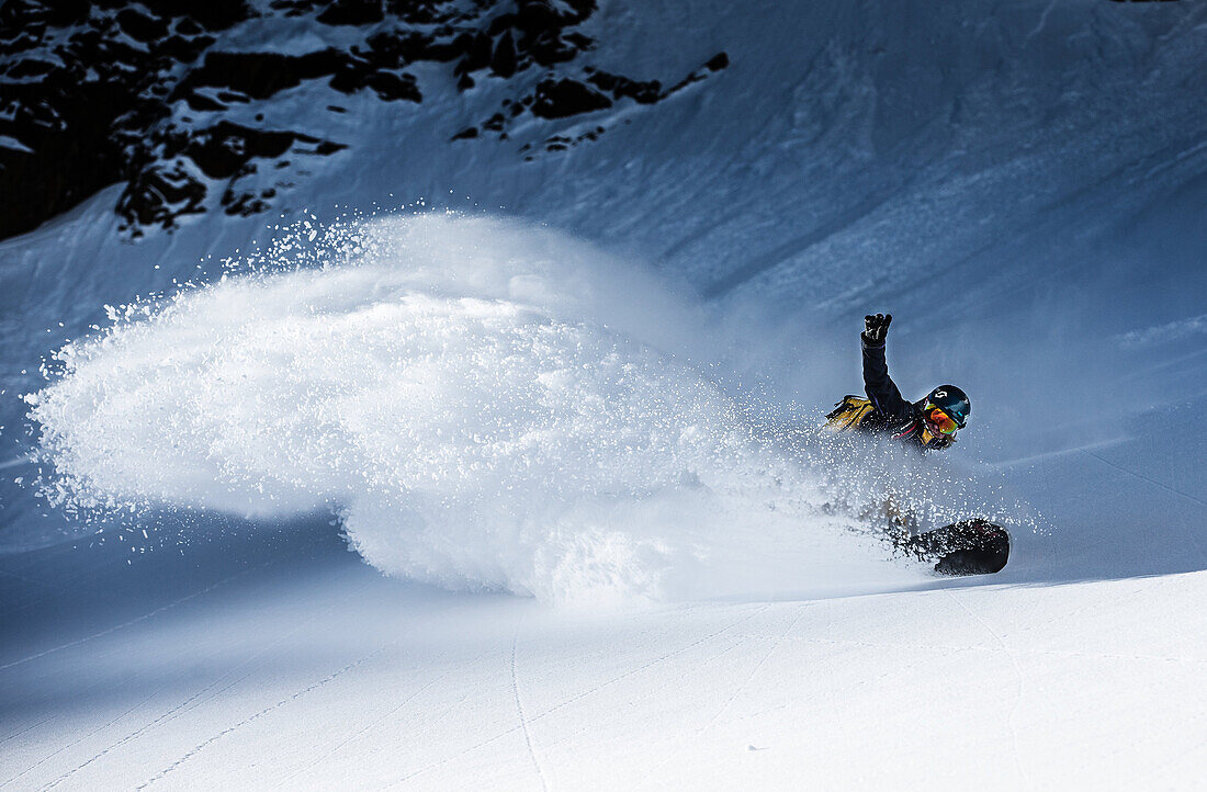 Young female snowboarder riding through deep powder snow in the mountains, Pitztal, Tyrol, Austria