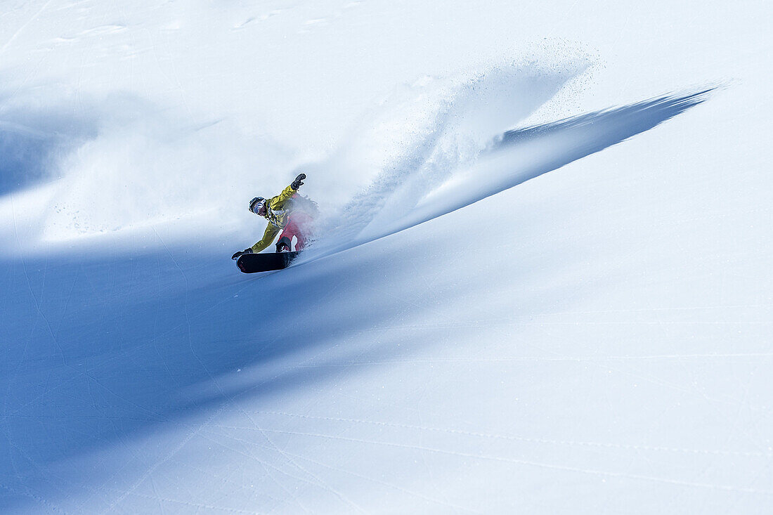 Young male snowboarder riding through deep powder snow in the mountains, Pitztal, Tyrol, Austria