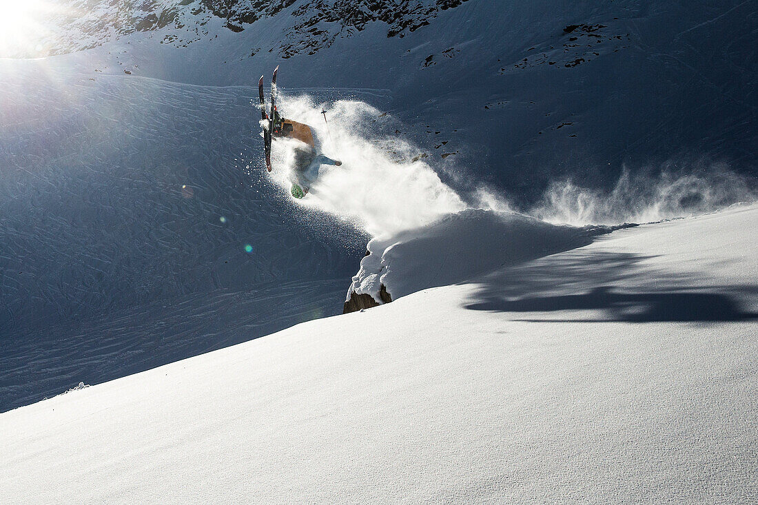 Junger Skifahrer macht einen Backflip über einen Felsen, Pitztal, Tirol, Österreich