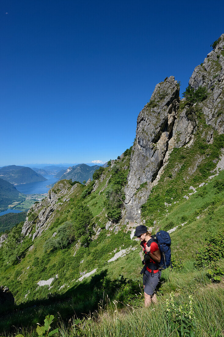 Hiker in front of Lake Lugano with the highest Swiss mountain, the snow-capped Dufourspitze (4634 m) in the Monte Rosa massif, Italy and Switzerland